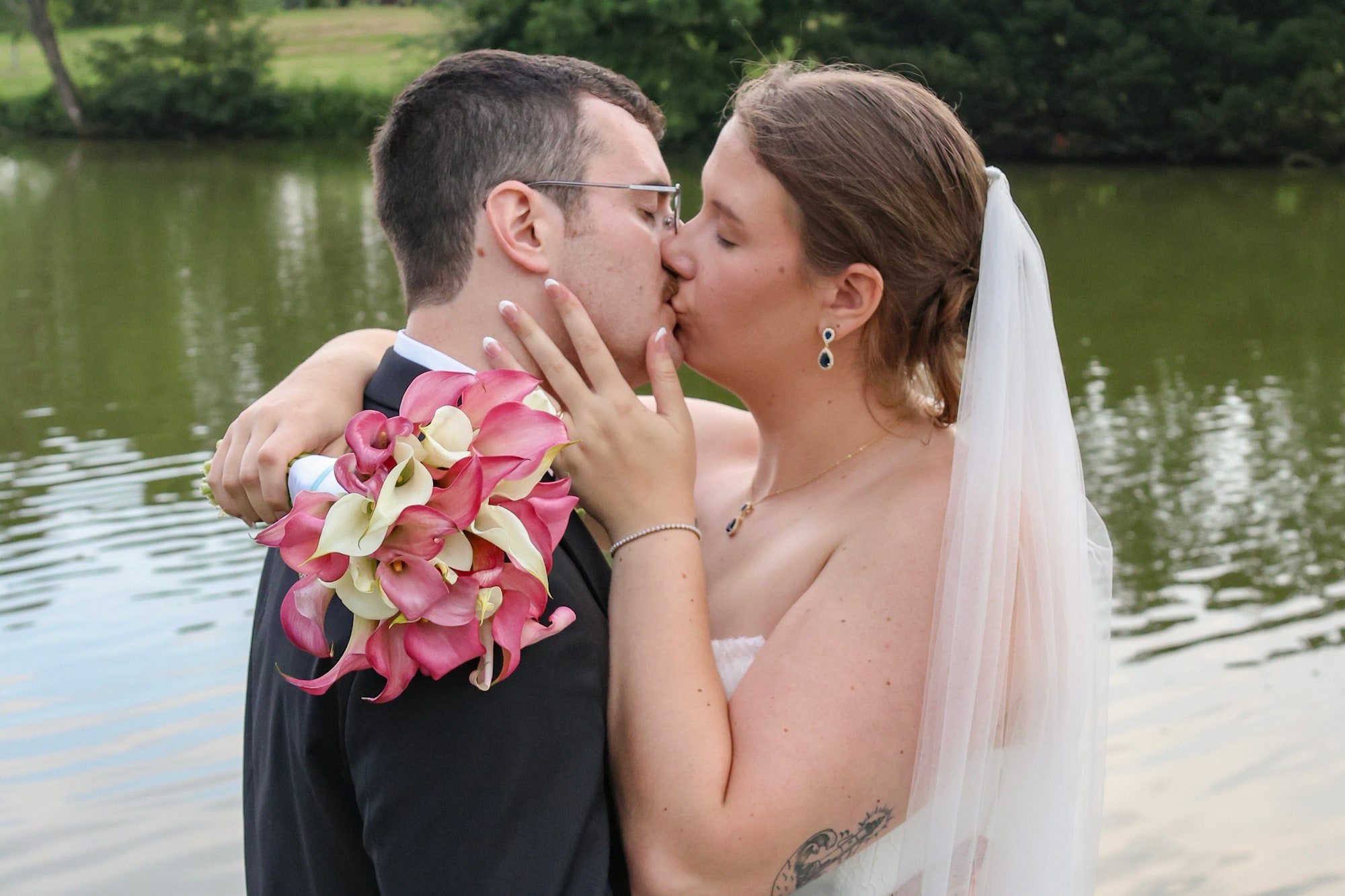 Bride and groom sharing a kiss beside the water